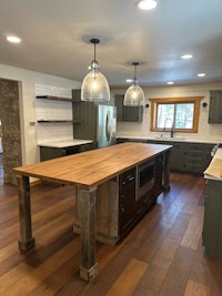 a kitchen with a wooden island and green cabinets