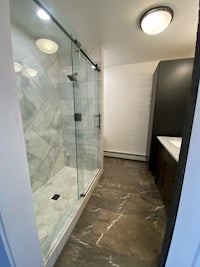 a bathroom with a glass shower stall and marble floors