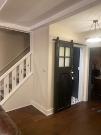 a living room with stairs and a black door