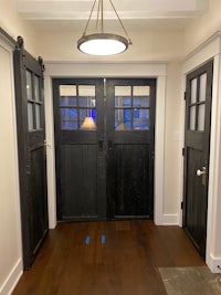 a hallway with two black doors and a light fixture