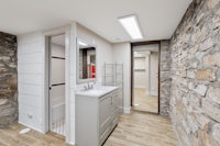 a bathroom with a stone wall and wooden floors
