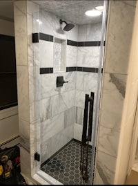 a shower with a black and white tiled floor