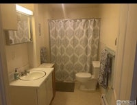 a bathroom with a toilet, sink and shower curtain