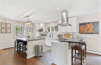 a kitchen with white cabinets and hardwood floors