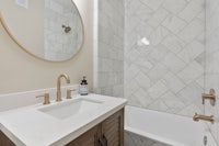 a bathroom with marble tile and gold fixtures