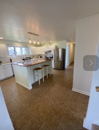 a view of a kitchen with tile floors and a refrigerator