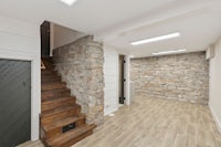 a basement with a stone wall and wooden stairs